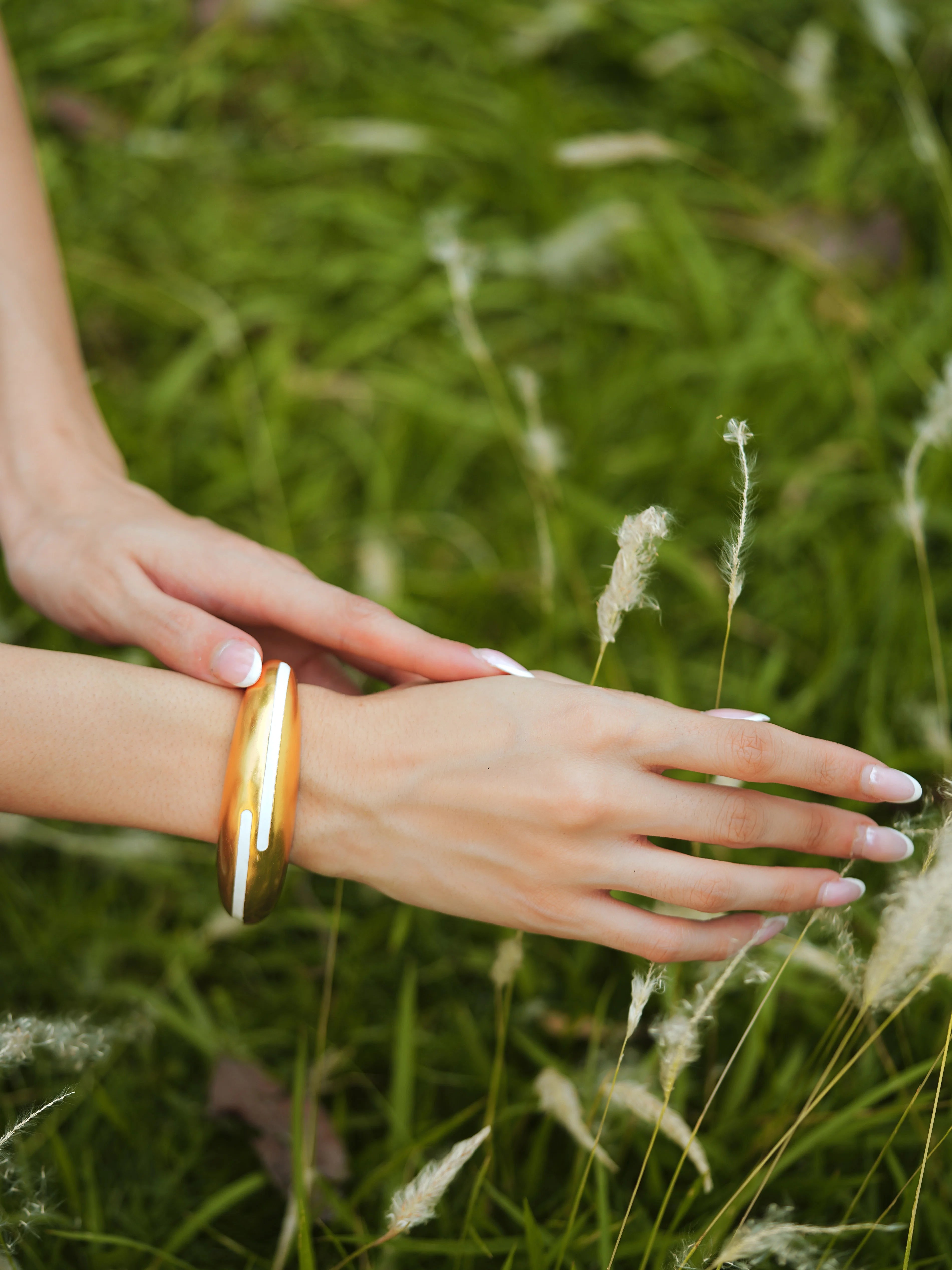 Varnika Arora white enamel gold bangle with intricate design, showcasing elegant jewelry craftsmanship and shiny finish.