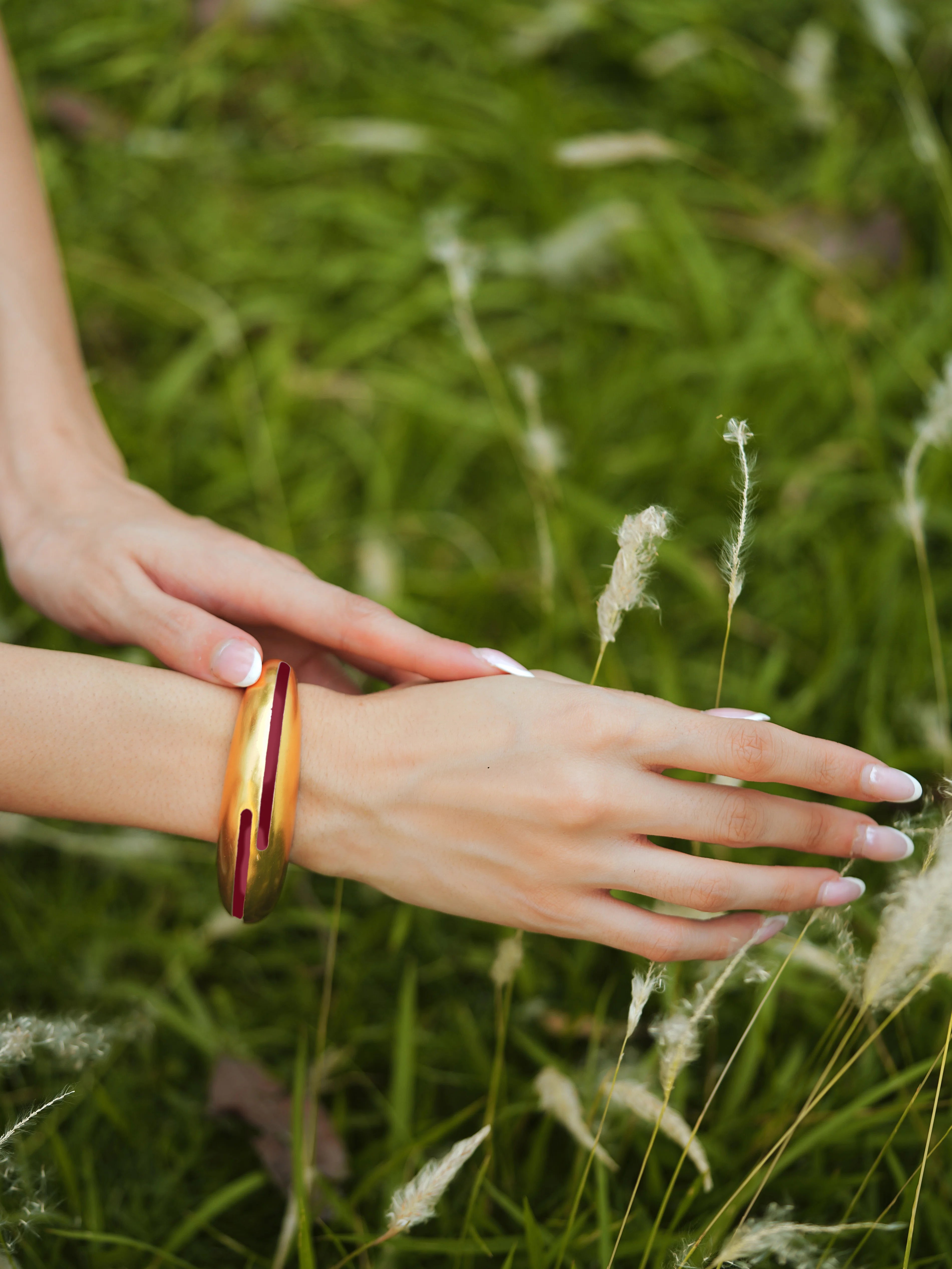 Maroon enamel gold bangle by Varnika Arora featuring a delicate circular design and intricate detailing on a plain background. Main image