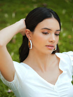 Varnika Arora Devine white enamel gold hoop earrings, showcasing sleek white enamel with gold accents and classic hoop design.