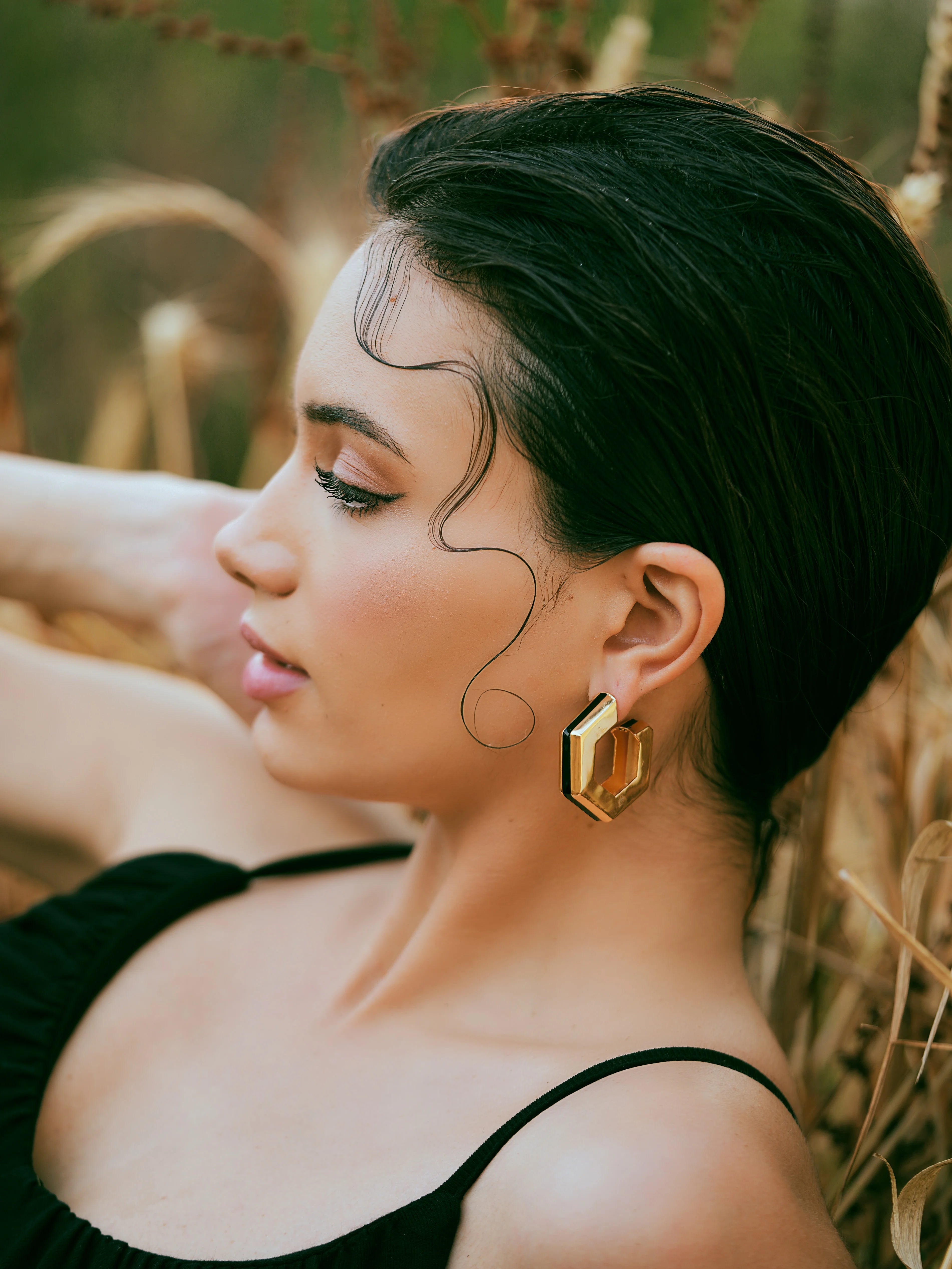 Varnika Arora Helixa black enamel gold hoops earrings hanging on display with shiny finish and intricate design
