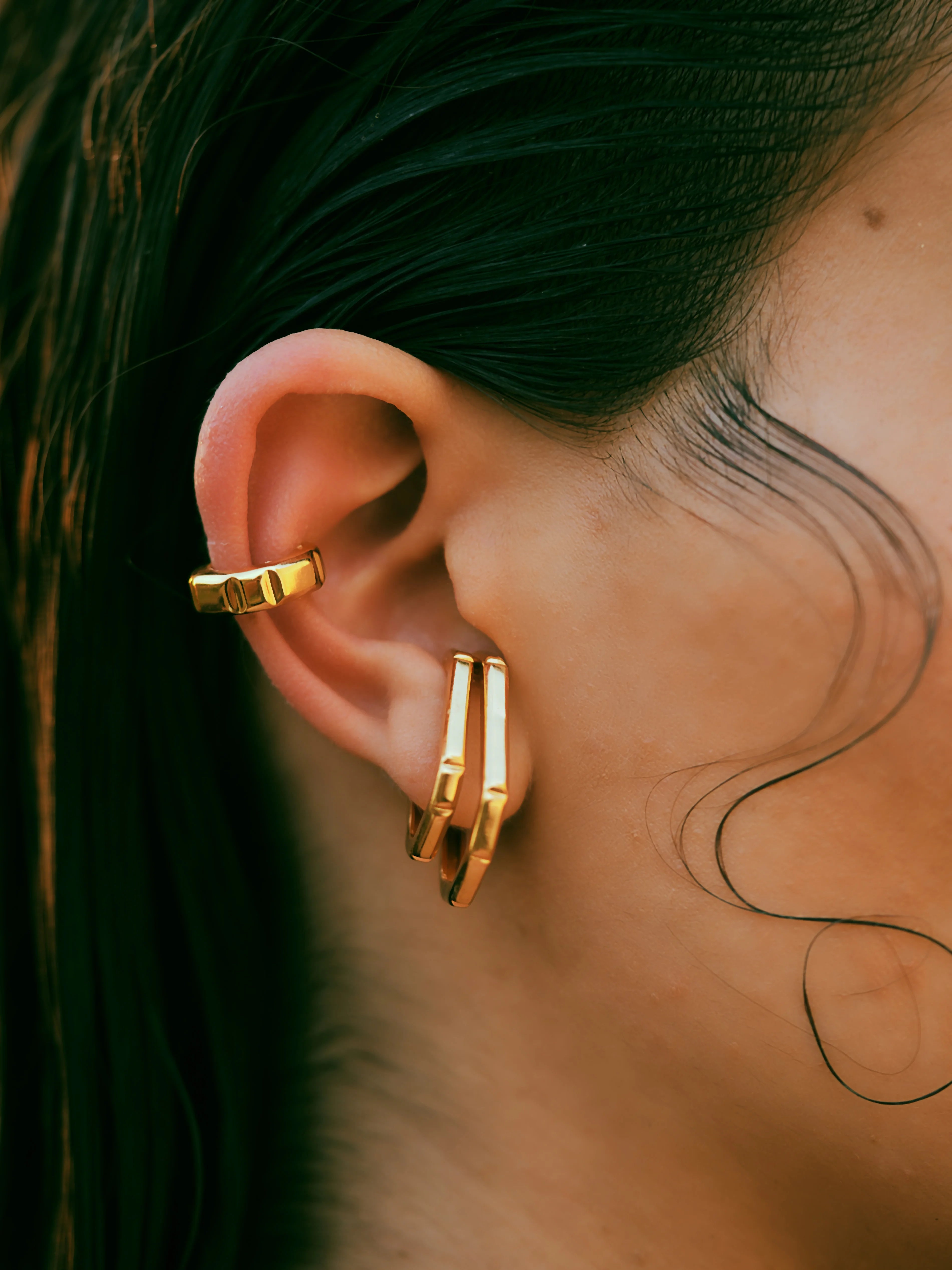 Varnika Arora Nova Gold ear cuff earrings with intricate design, worn on a model's ear in a close-up shot